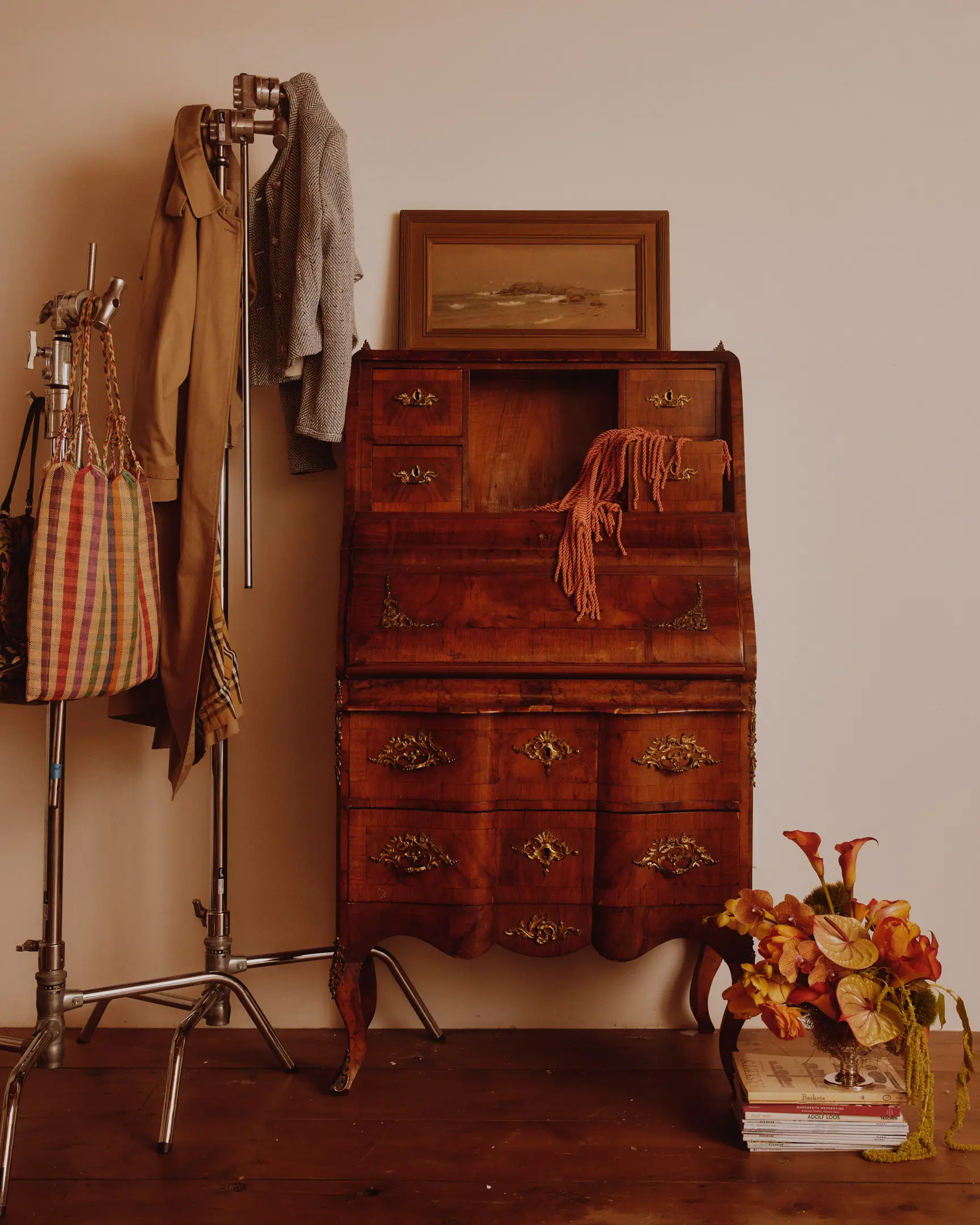 Vintage dresser from NAN Collective with C-Stands holding purses and jackets, and floral arrangement in the studio of Lulu LaFortune. The studio of Lulu LaFortune, a designer based in Los Angeles, Ca. Shot originally for House Beautiful publication.